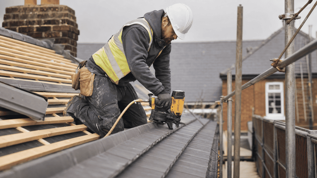 Best Roofing Nailer Guide: What Roofing Nailers Are Used For & How to Use One 4 A roofer busy at work with a roofing nailer